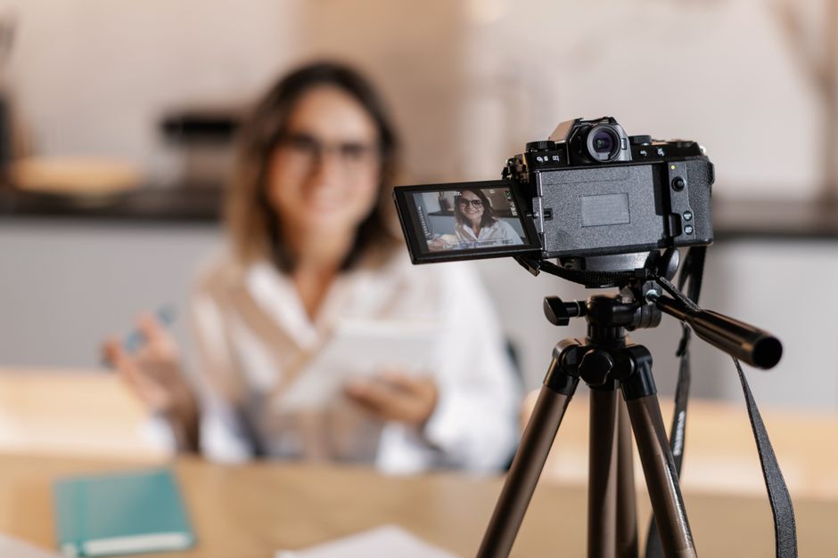 Woman vlogger using a camera and tripod for content creation indoors.