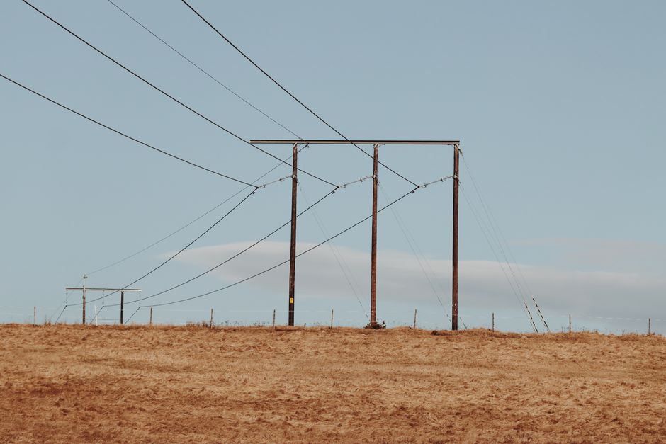 Power lines stretching over a dry landscape under a clear blue sky in Jönköping, Sweden.